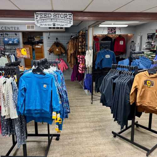 Clothing store interior with casual wear, including blue sweatshirts and hoodies, neatly displayed on racks. A 