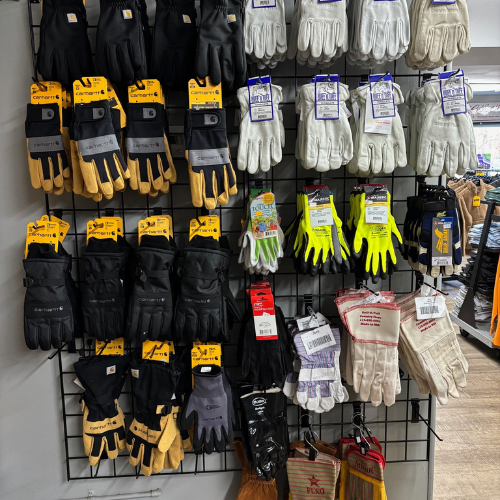 A display of various work gloves is neatly organized on a rack. The gloves vary in color, including black, white, yellow, and bright neon.