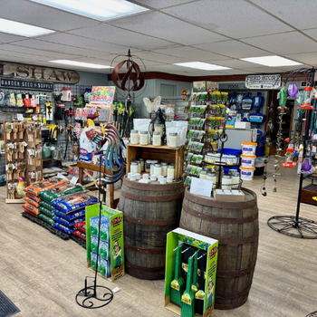 Image of a store interior with a rustic feel, displaying garden and farm supplies. Wooden barrels, seed packets, tools, and vibrant displays create a cozy, welcoming atmosphere.