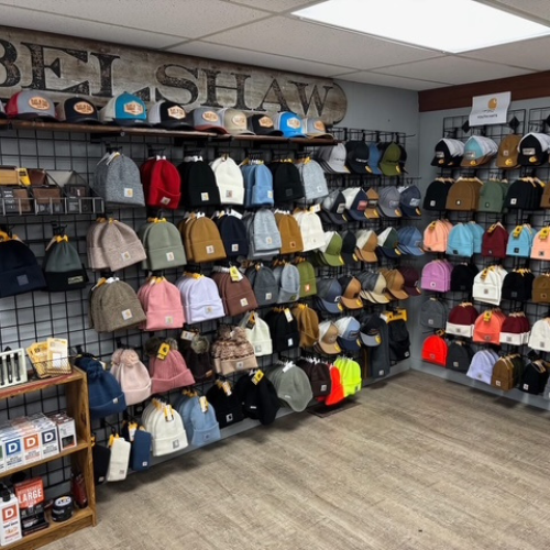 A cozy store with colorful beanies and caps displayed on metal grids covering two walls. The vibrant hats create an inviting, cheerful atmosphere.